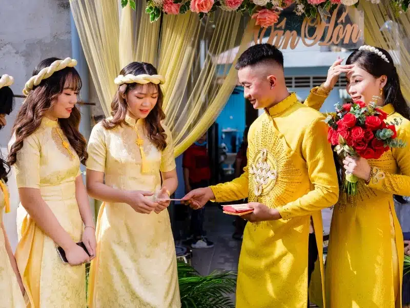 A traditional wedding in Vietnam, with a Vietnamese man and women getting married and wearing yellow wedding clothing