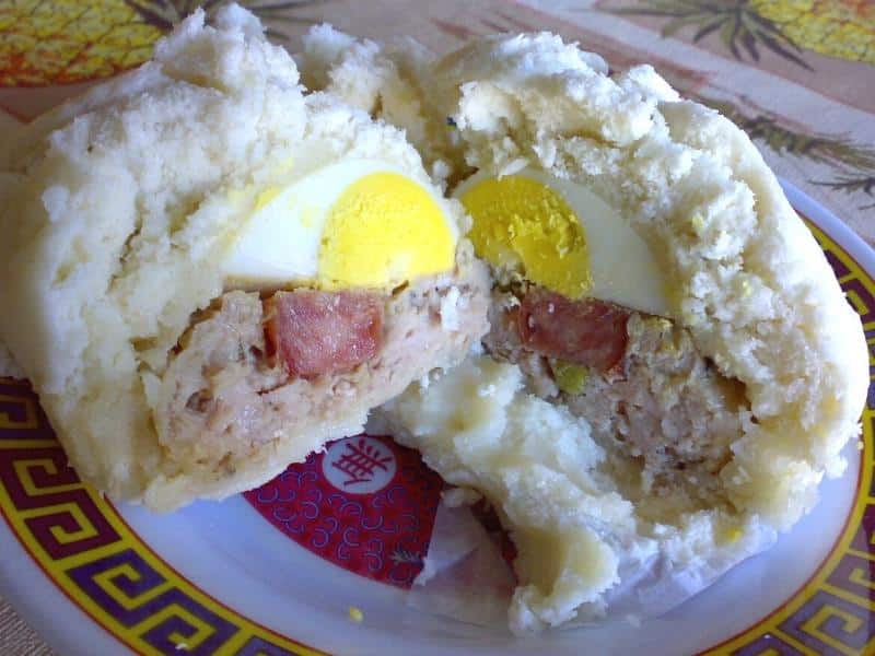 Steamed bun (bahn bao) pulled apart in half to show the sausage and egg inside