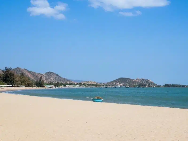 An empty beach in Vietnam at Cam Ranh, with a single round boat on it