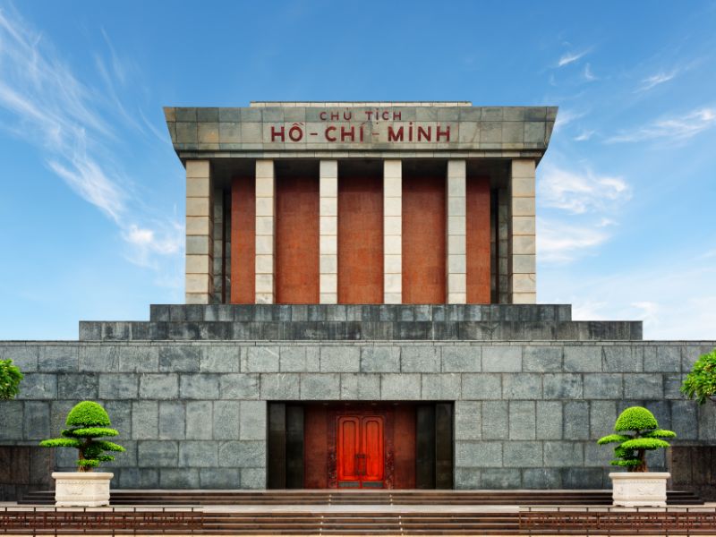 A towering cement mausoleum building that says Ho Chi Minh on it