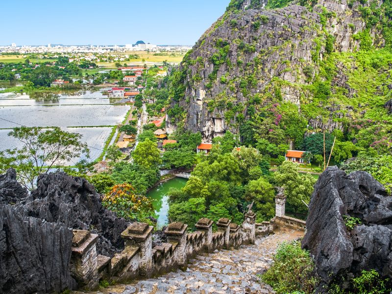 Looking down a steep set of stone steps with cliffs and rice paddies at the bottom