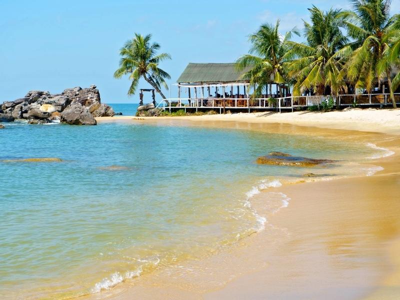 Looking down a beach on Phu Quoc island with palm trees and a shack at the end