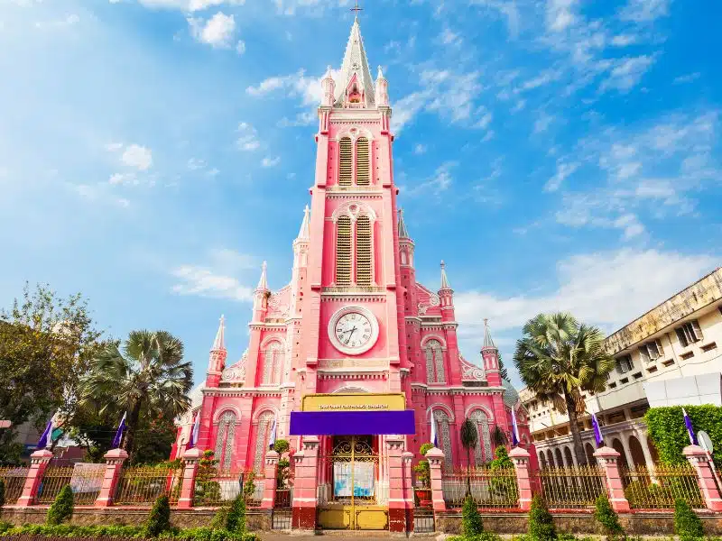 A tall pink church with fence in front