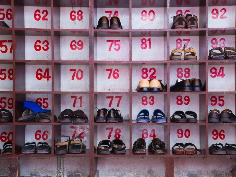 A shoe rack with numbered cubbies, some empty, and some with shoes in them