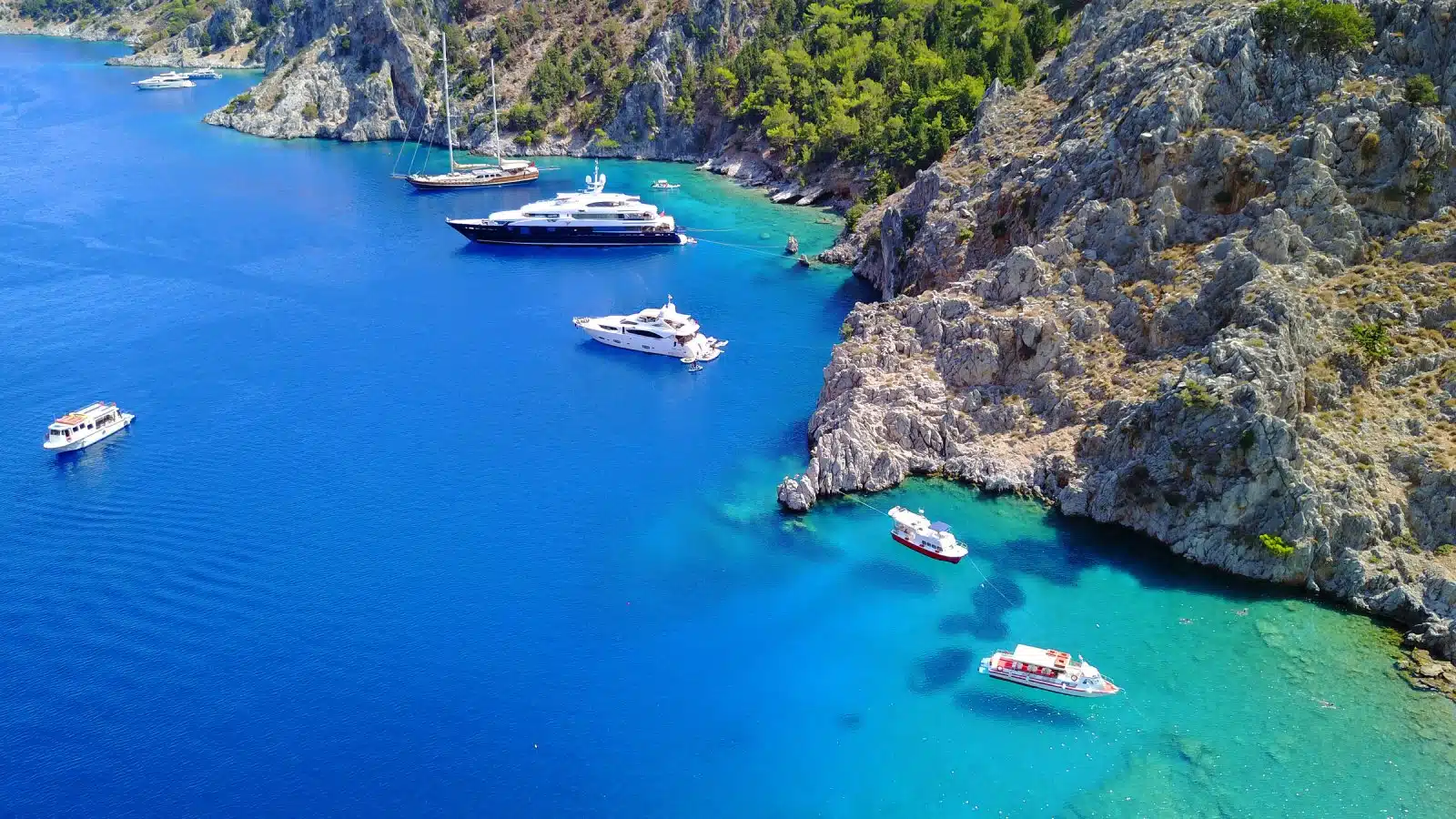 Aerial bird's eye view photo taken by drone of tropical rocky seascape with yachts docked and turquoise - sapphire clear waters