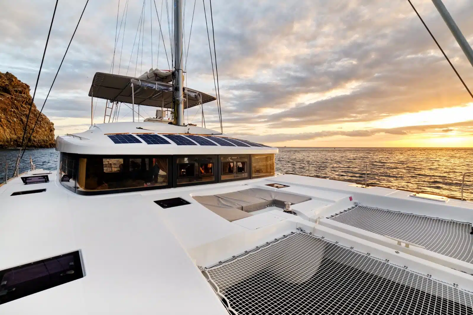 Solar powered catamaran at sunset, fully sustainable and powered by solar energy, charging batteries aboard a sailboat, vessel in ocean waters, nobody. Photovoltaic panels renewable eco energy concept