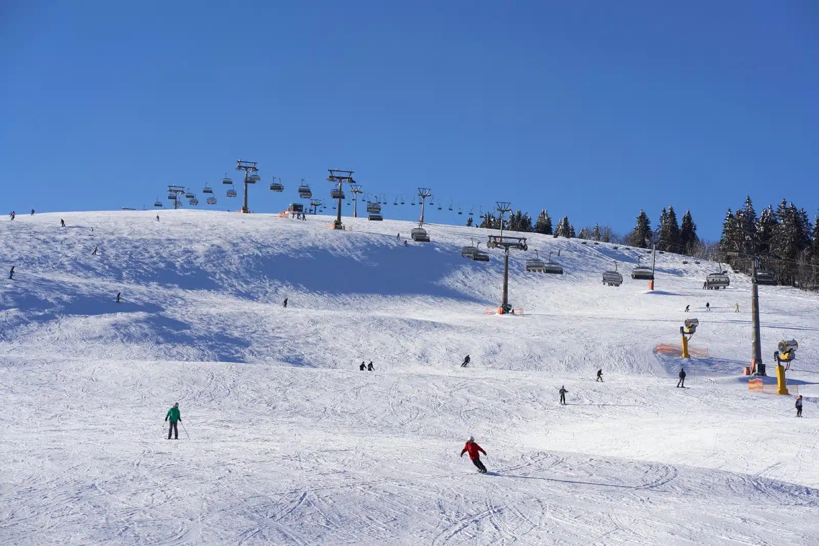 Ski and snowboard riders on the white snow slope