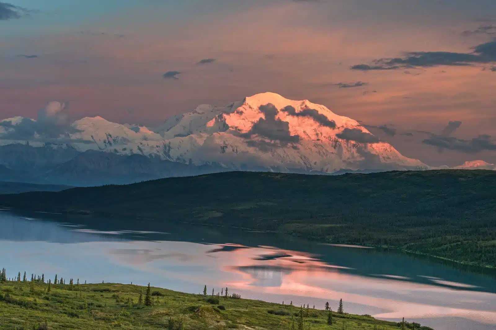 view of alaska's mount denali reflected in calm wonder lake, with sunset light